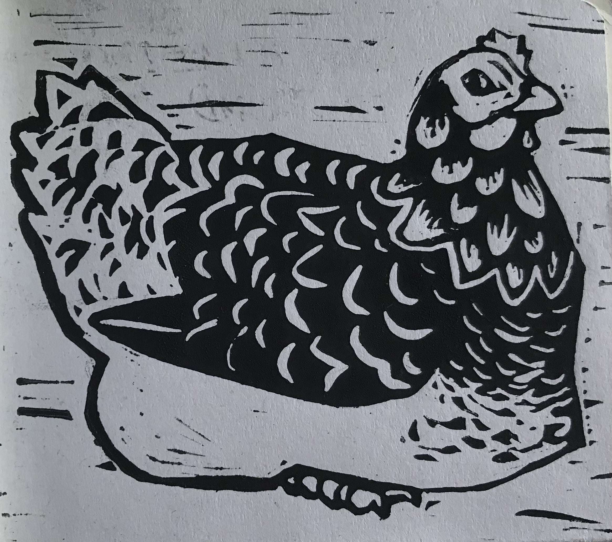 a black and white linocut print of a speckled hen sitting.  she looks at the viewer.